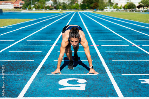 Woman athlete on running field in starting position photo