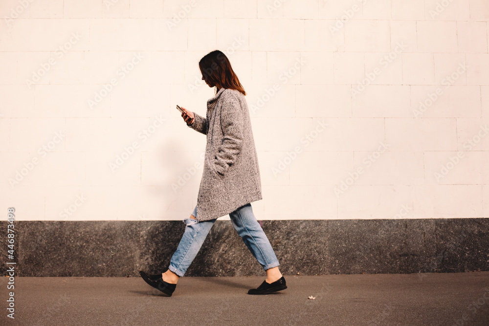 Side view of transgender woman using smart phone walking against wall Side view of transgender woman using smart phone walking against wall