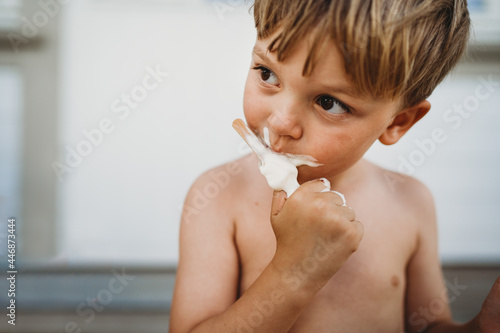 Cute young boy eating ice cream looking to the side outside in summer photo