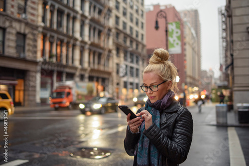 Attractive woman using smartphone on busy urban street photo