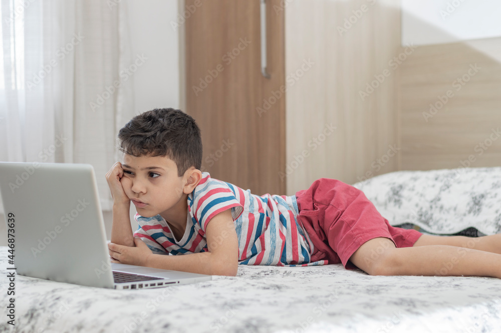Young boy child lying on bed using a laptop. Online class lesson Stock ...