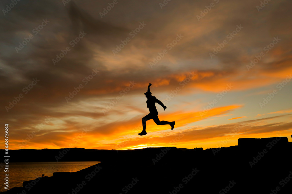 Silhouette of man jumping with cap in the sunset Silhouette of man jumping with cap in the sunset