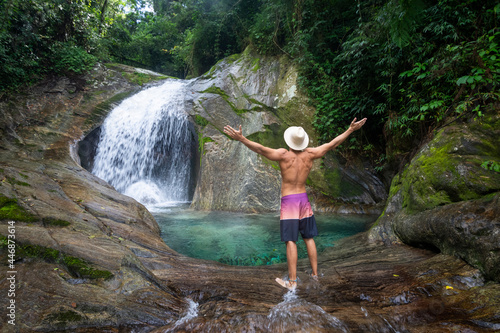 Man with straw hat on beautiful crystal clear water rainforest pool photo