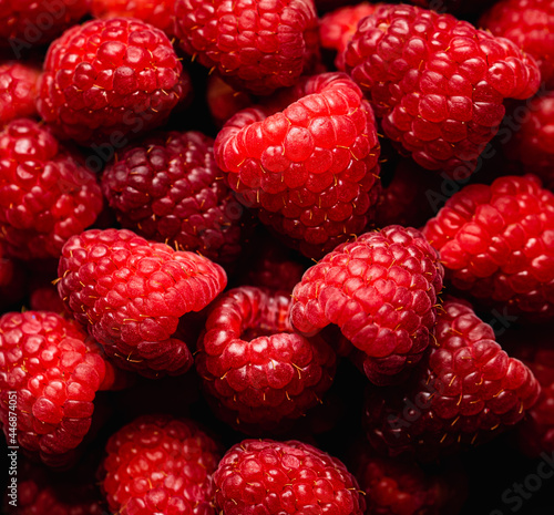 Close up of a bunch of fresh, ripe red raspberries.