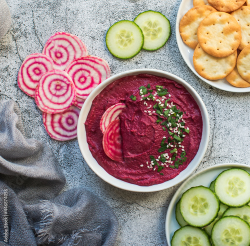 Bowl of beet hummus, vegetables and crackers on gray backgrounf. photo