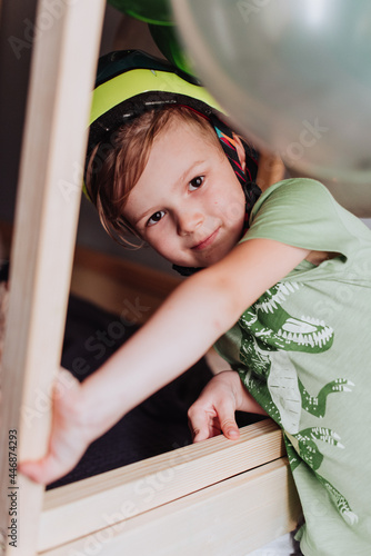 5 years boy playing in his room, wearing green t-shirt with dinosaurus print and dino helmet photo