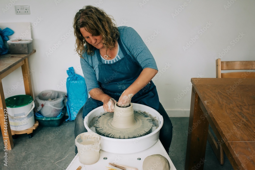 woman concentrating on spinning clay on a pottery wheel at home studio woman concentrating on spinning clay on a pottery wheel at home studio