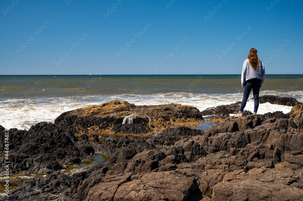 Female Standing On A Rocky Coastline Female Standing On A Rocky Coastline