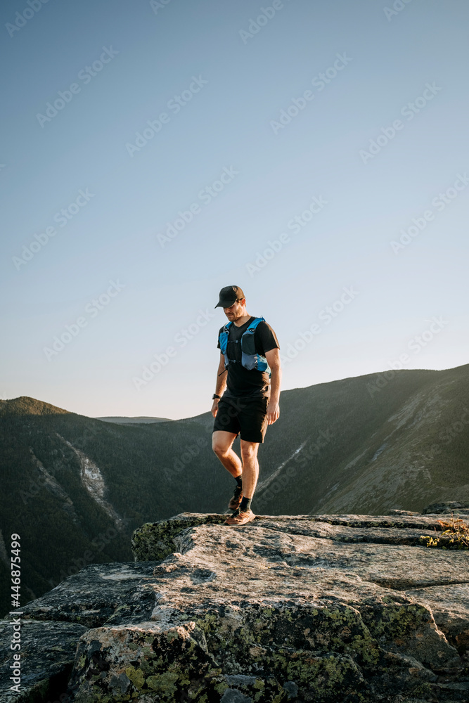 Male trail runner hikes on granite in White Mountains, New Hampshire Male trail runner hikes on granite in White Mountains, New Hampshire