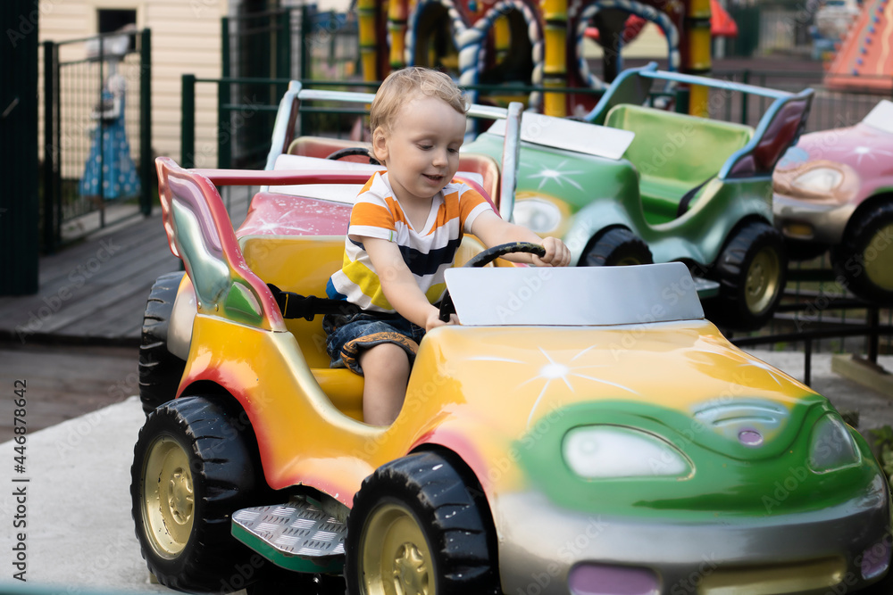 A child rides a car in the amusement park. A child rides a car in the amusement park.