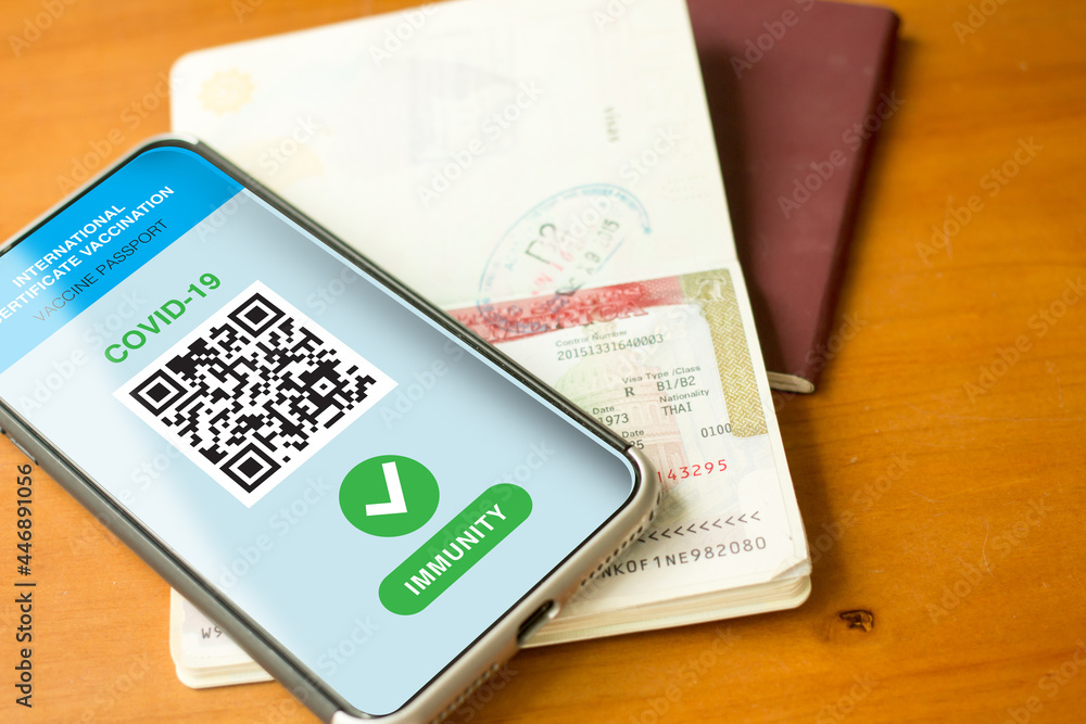Fototapeta premium Bangkok, Thailand, July 23, 2021. A passport and a smartphone with a Certificate of Vaccination against Covid-19 disease are arranged on a wooden table.