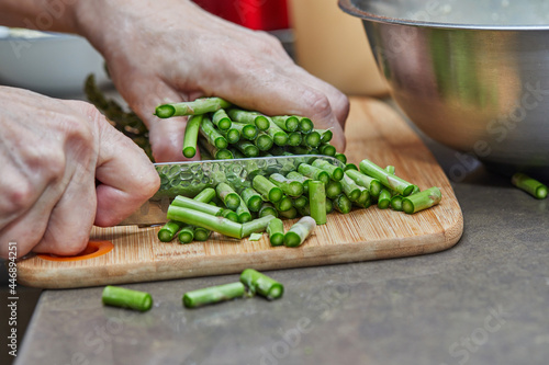 Chef cuts asparagus with knife to make baked goods with asparagus and peas. Step by step recipe