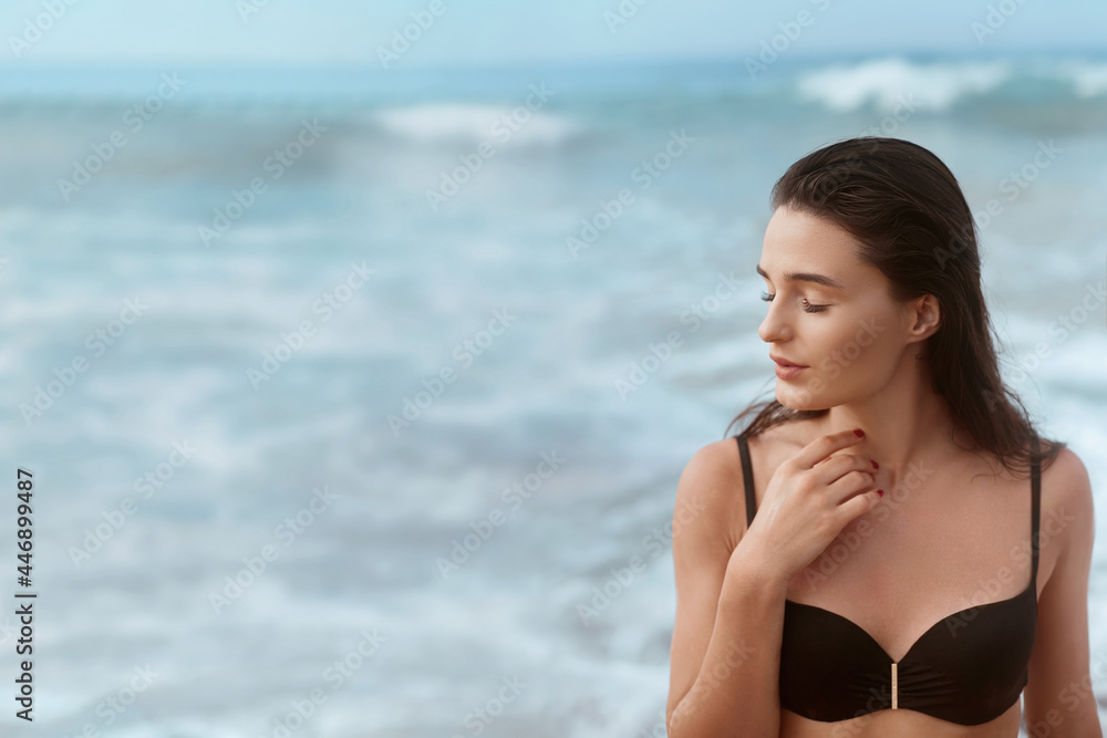 Portrait of young woman in black bikini on tropical beach looking at camera. Beautiful girl in swimwear Portrait of young woman in black bikini on tropical beach looking at camera. Beautiful girl in swimwear