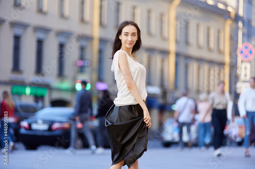 Slender woman in black skirt walks outdoors in summer.