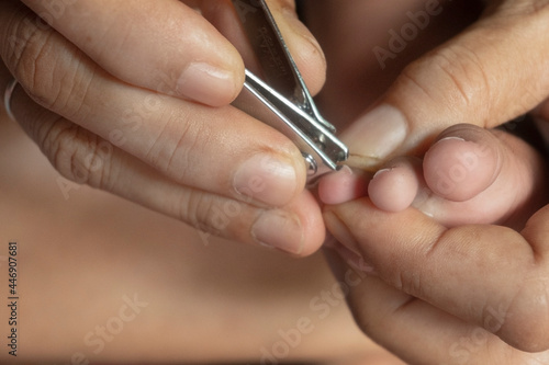 Mother s hand to cut toenails for the baby. Closer.
