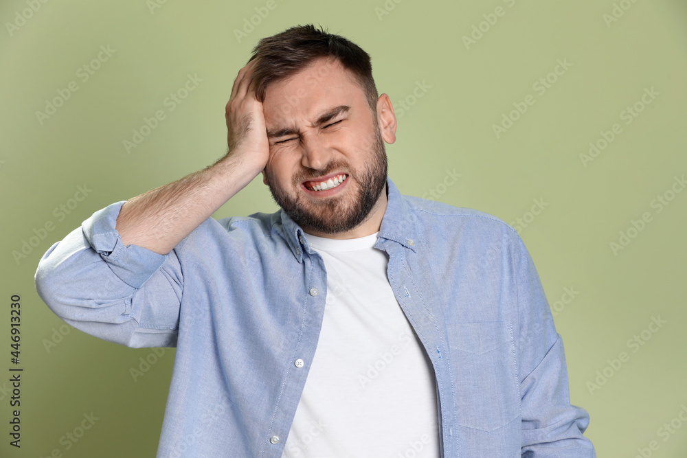 Man suffering from migraine on light green background Man suffering from migraine on light green background