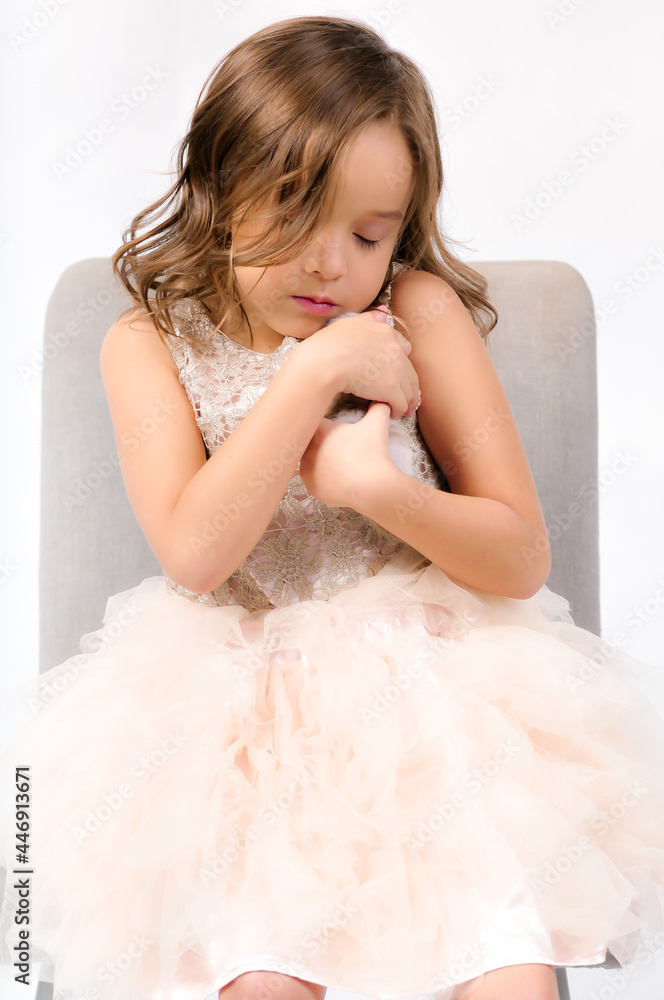 Portrait of happy pretty curly little girl with kitty cat sitting on the chair and posing over white background Portrait of happy pretty curly little girl with kitty cat sitting on the chair and posing over white background