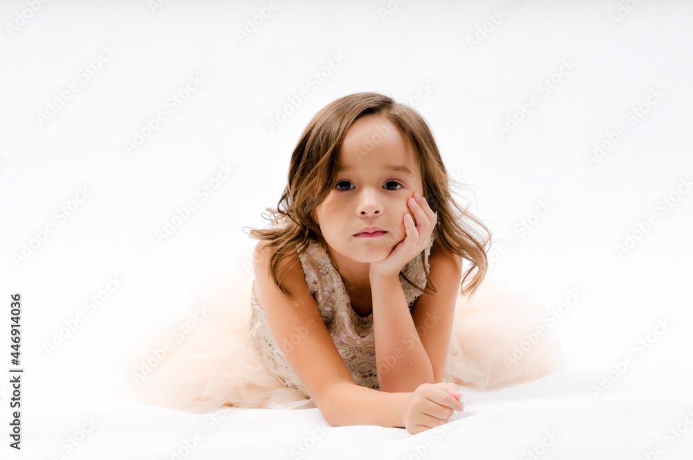 Portrait of happy pretty curly little girl laying on the floor and posing over white background , happy face girl concept Portrait of happy pretty curly little girl laying on the floor and posing over white background , happy face girl concept