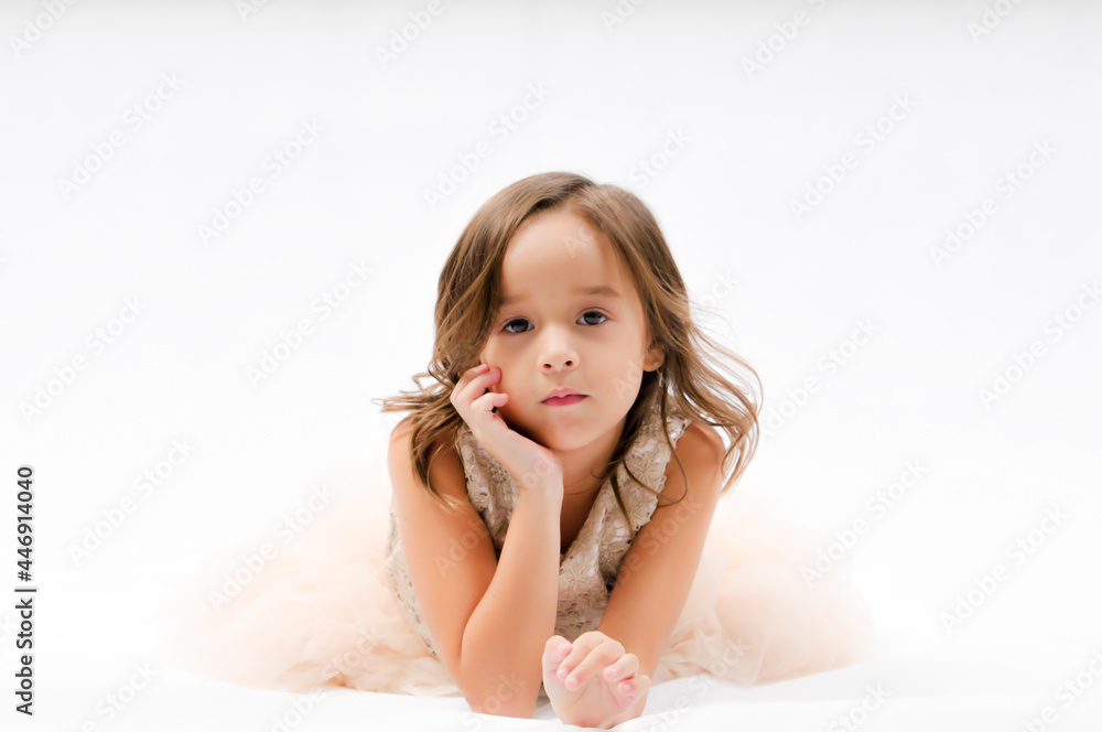 Portrait of happy pretty curly little girl laying on the floor and posing over white background , happy face girl concept Portrait of happy pretty curly little girl laying on the floor and posing over white background , happy face girl concept
