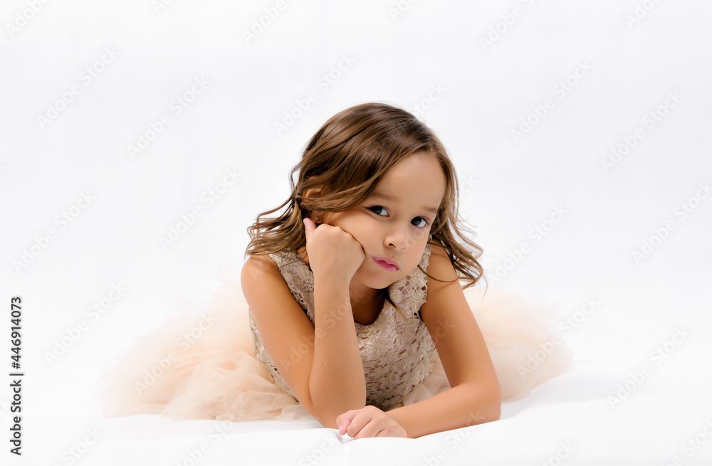 Portrait of happy pretty curly little girl laying on the floor and posing over white background , happy face girl concept Portrait of happy pretty curly little girl laying on the floor and posing over white background , happy face girl concept