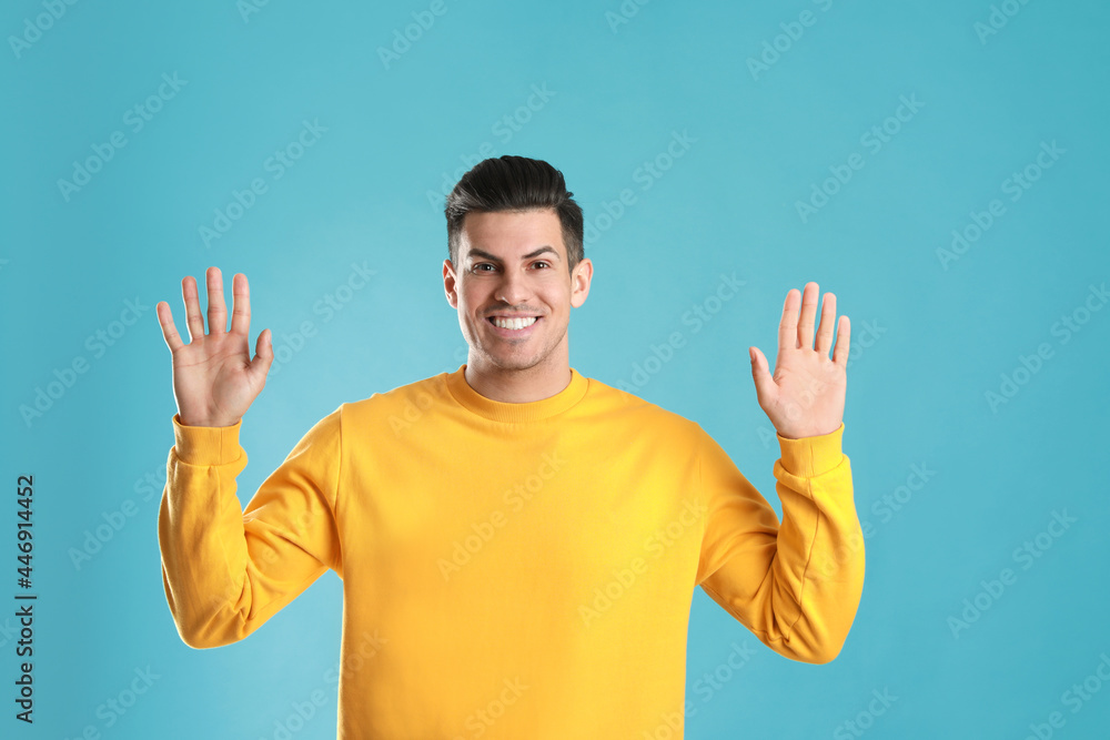 Cheerful man waving to say hello on turquoise background Cheerful man waving to say hello on turquoise background