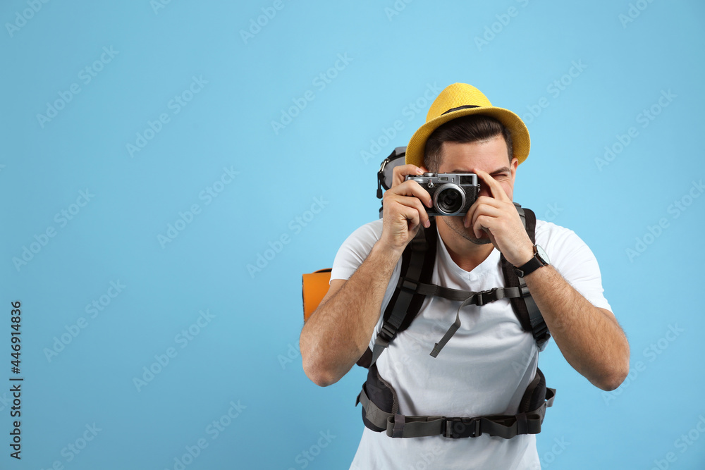 Male tourist with travel backpack taking picture on turquoise background, space for text Male tourist with travel backpack taking picture on turquoise background, space for text