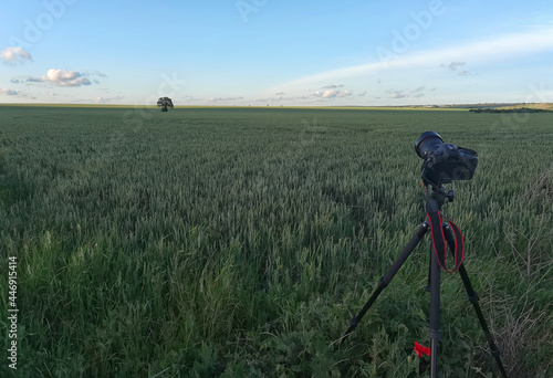 A camera with a lens on a tripod, ready for taking photos or videos in nature. Photographing and filming landscapes, wildlife.