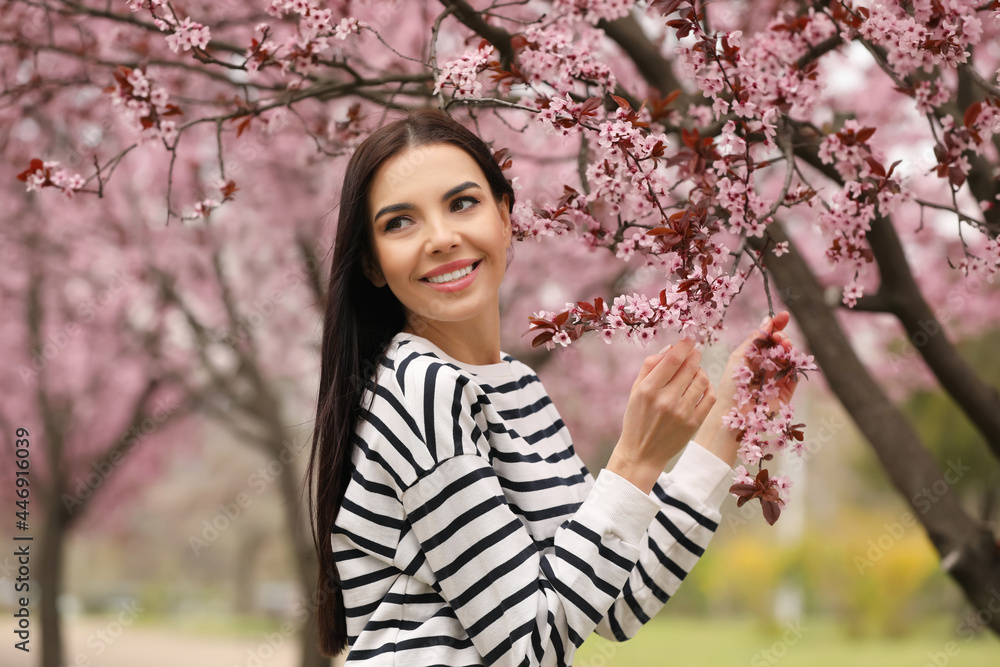 Pretty young woman near blooming tree in park. Spring look Pretty young woman near blooming tree in park. Spring look