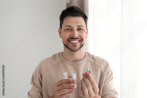 Fotografia Man with glass of water taking pill at home