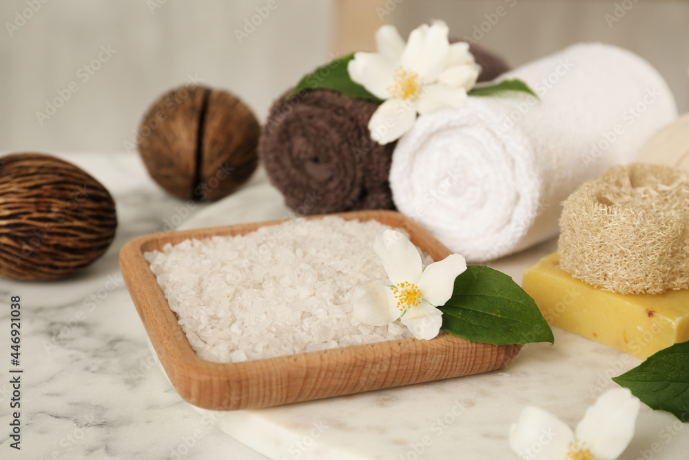 Composition with beautiful jasmine flowers and sea salt on white marble table Composition with beautiful jasmine flowers and sea salt on white marble table
