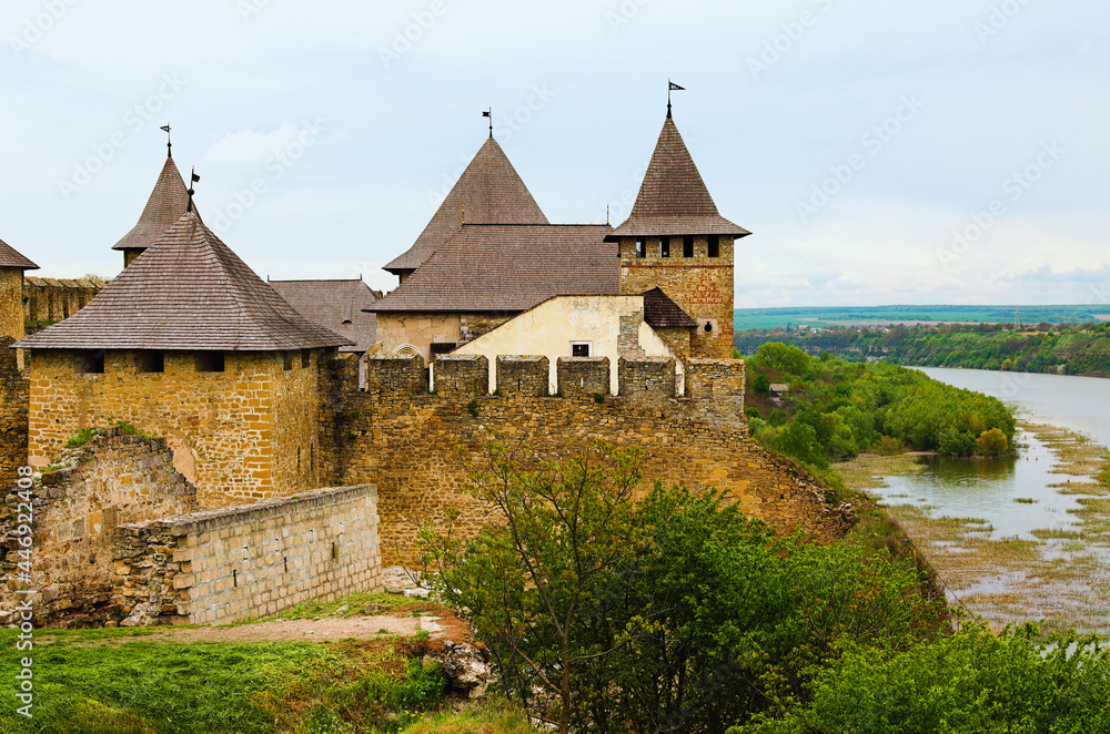 Detailed view of oldl castle in the bank of Dnister River. Ruins of fortifications. High stone walls with massive towers. Blue sky background.  Famous touristic place and travel destination in Ukraine