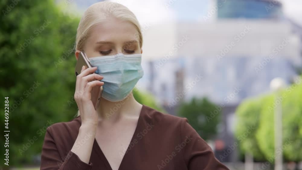 A woman in a medical mask nervously looks at her watch and talks on the phone. Late for a meeting. Close-up, slow motion, HD. A woman in a medical mask nervously looks at her watch and talks on the phone. Late for a meeting. Close-up, slow motion, HD.