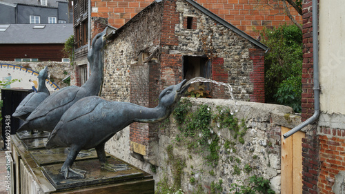 bronze geese with running water flowing from their mouths, in front of old red brick houses, Le Jarden du Tripot, Tripot's gardens, Honfleur, France