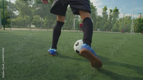 Close-up back view of soccer player legs in football boots and sportswear, dribbling to goal, demonstrating close ball control, quick feet, performing football tricks and moves, kicking ball on pitch