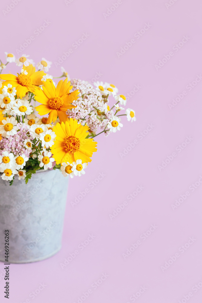 Beautiful summer flowers in a vintage pot on a pink background.