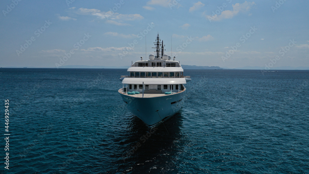 Aerial drone photo of luxury mega yacht with wooden deck and pool facilities anchored in Mediterranean open ocean deep blue bay