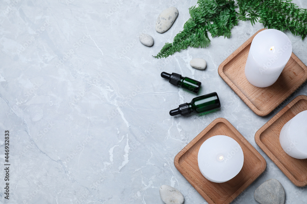 Fototapeta premium Burning candles, stones and essential oil on grey marble table, flat lay. Space for text