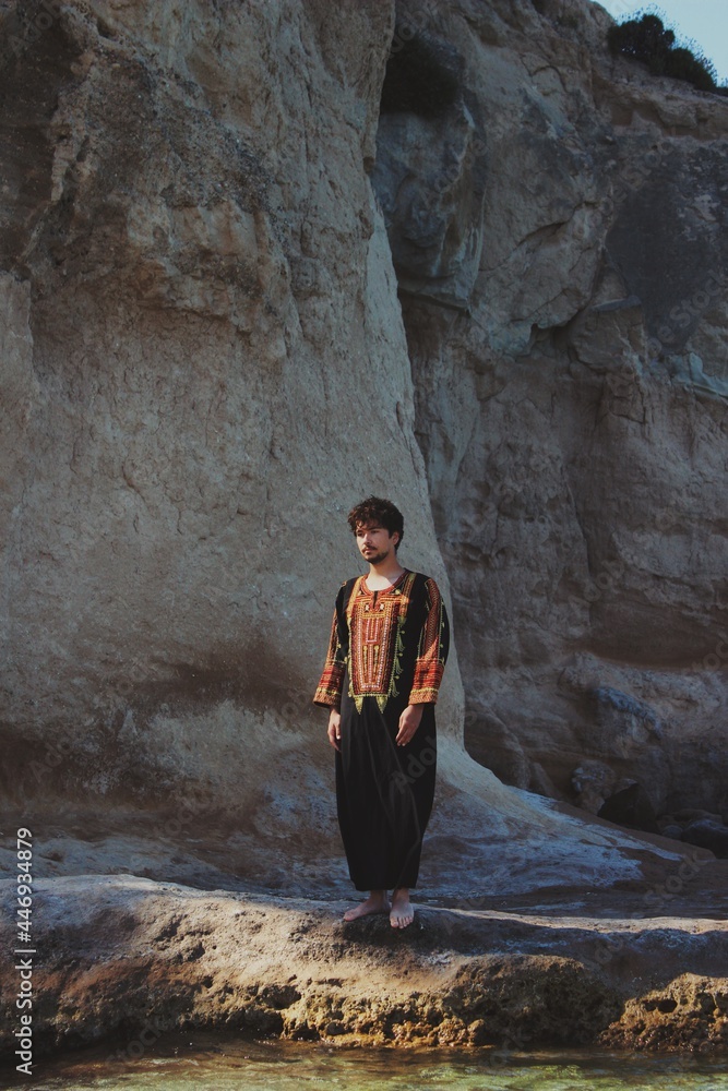 portrait of young man looking up with anatolian / ottoman traditional clothing / kaftan in Turkish badlands 