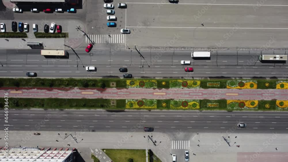 Drone aerial, video shooting from above on a city street, cars, people. People walking on the sidewalk and vehicles. Multi-colored paving slabs and a lawn with flowers on a city street. Drone aerial, video shooting from above on a city street, cars, people. People walking on the sidewalk and vehicles. Multi-colored paving slabs and a lawn with flowers on a city street.