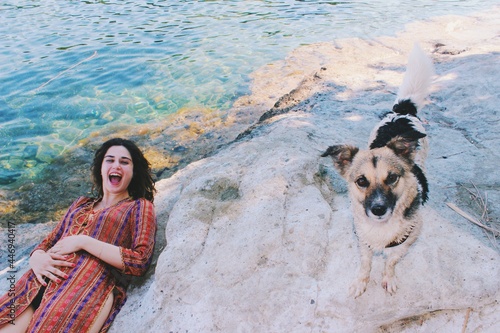 Funny happy Portrait of young woman wearing turkish traditional costume at the sea surprised by stray dog 