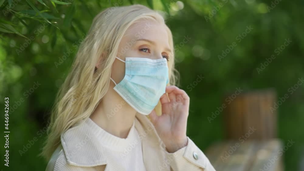 Young beautiful blonde woman takes off a medical mask and sniffs a yellow dandelion. The joy of fresh air and the scent of flowers. Life during the coronavirus epidemic. Close-up, slow motion, HD. Young beautiful blonde woman takes off a medical mask and sniffs a yellow dandelion. The joy of fresh air and the scent of flowers. Life during the coronavirus epidemic. Close-up, slow motion, HD.