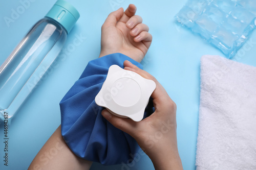 Woman with cold compress on light blue background, top view. Heat stroke treatment photo