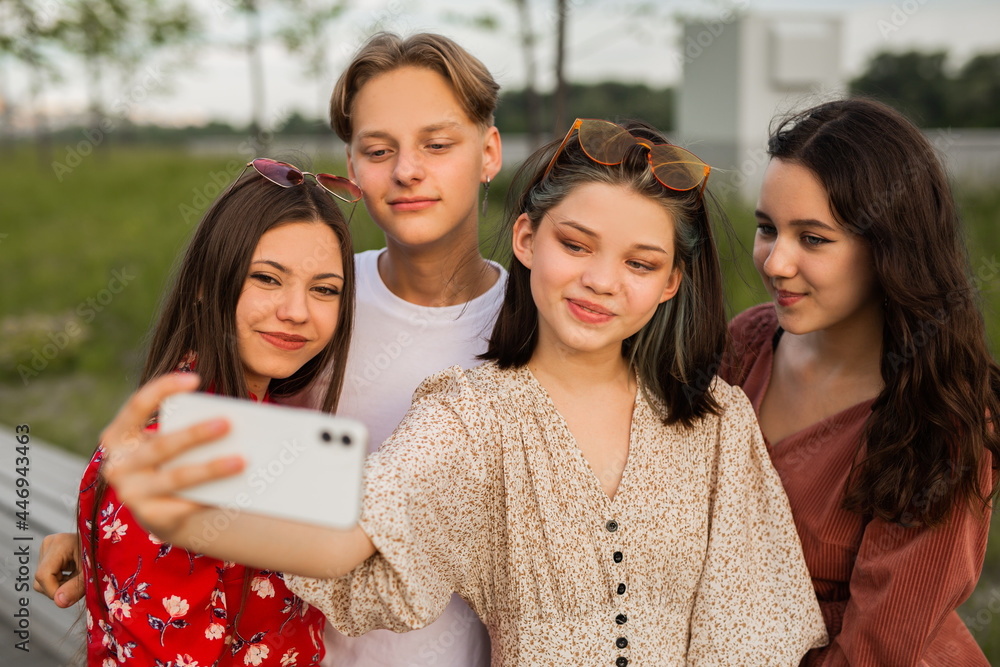 beautiful young friends are photographed on the phone in the summer park beautiful young friends are photographed on the phone in the summer park