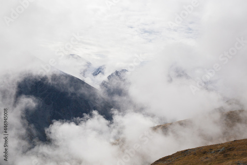 Mountains covered with clouds. Mountain peaks between clouds. Photo from above. Soft focus. Selective focus on distant mountain peaks.