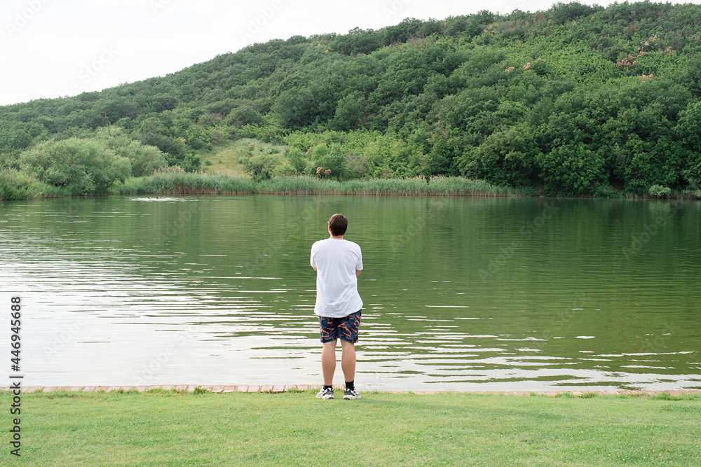 Back view of a man standing near the lake Back view of a man standing near the lake
