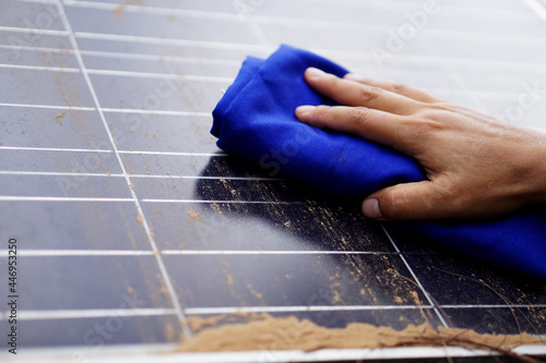 Photovoltaic surface is cleaned by hand hold cloth to clean dirty and dusty. Concept : Cleaning surface of photovoltaic panels to get high quality and efficiency of taking power energy from the sun. 