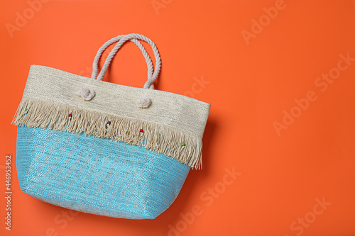 Stylish beach bag on orange background, top view. Space for text