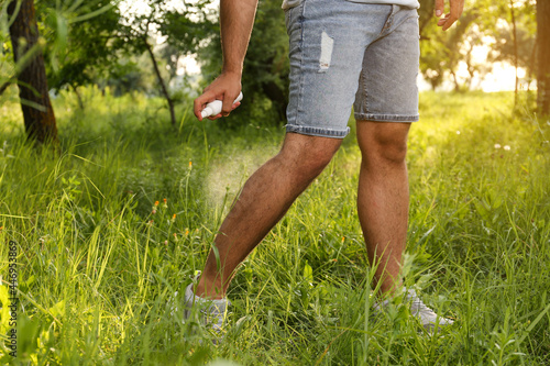 Man applying insect repellent on leg in park, closeup. Tick bites prevention