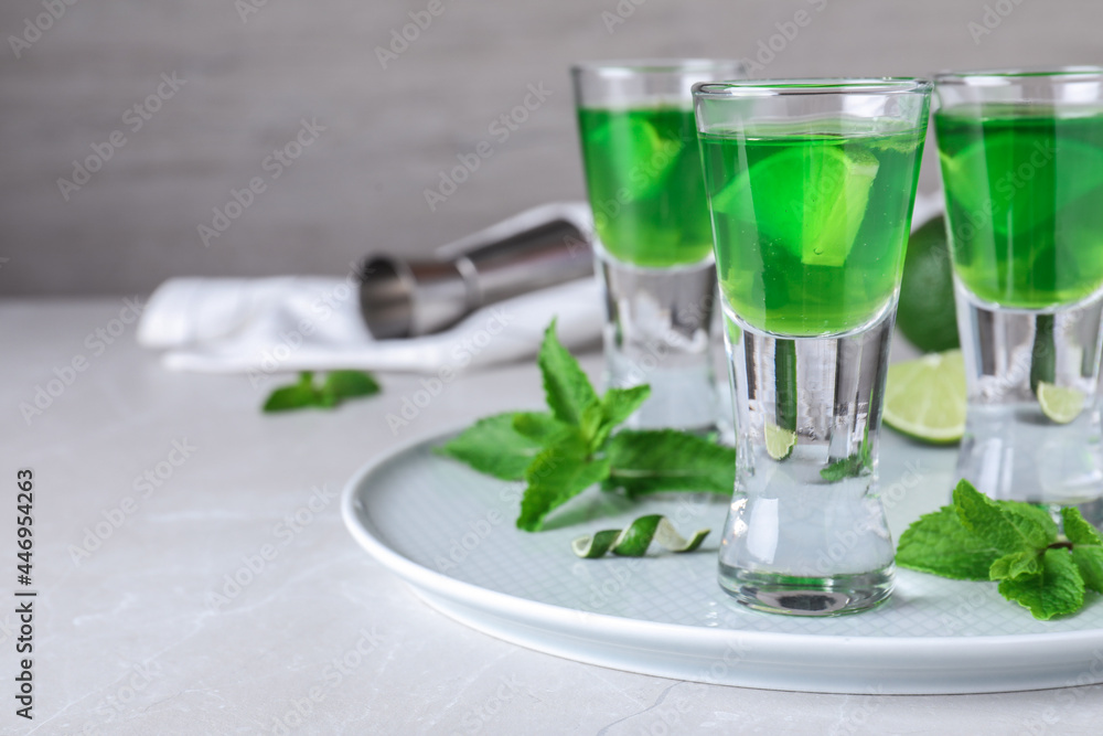 Delicious mint liqueur with lime and green leaves on white table. Space for text Delicious mint liqueur with lime and green leaves on white table. Space for text