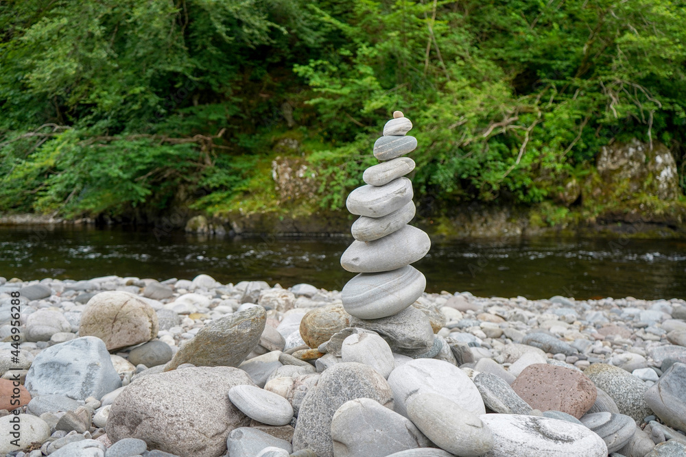 Small stones and pebbles stacked on top of each other beside a river
